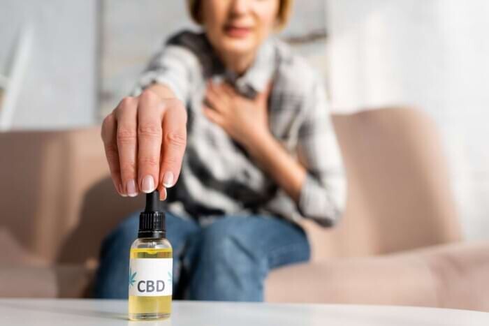 Cropped view of a woman holding a bottle with CBD lettering